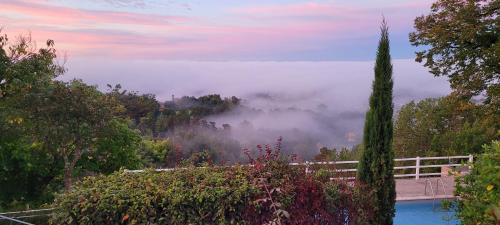 a view of a foggy valley with a swimming pool at Le Clos Des Etoiles in Le Bugue