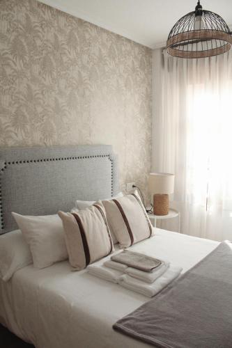 a bedroom with a bed with white sheets and a chandelier at El Maltés in Cudillero
