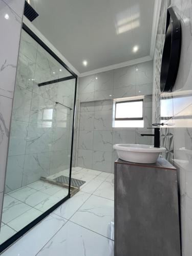 a bathroom with a glass shower and a sink at Rabi’s guesthouse in Mahikeng