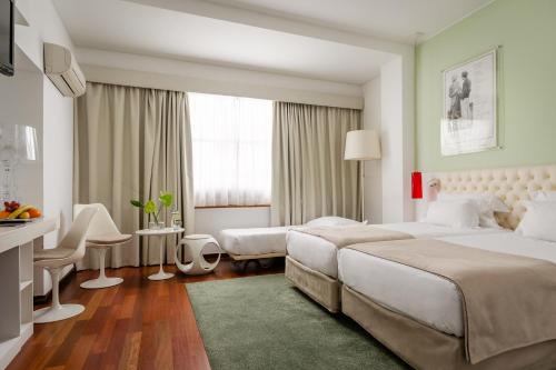 um quarto de hotel com duas camas e uma secretária em Hotel Florida em Lisboa