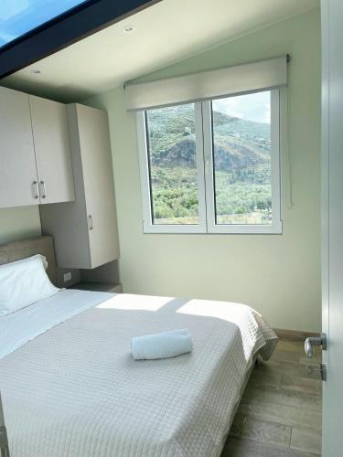 a bedroom with a white bed with a window at Aria's Apartment 2 in Himare