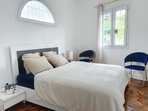 - une chambre blanche avec un grand lit et deux chaises bleues dans l'établissement Amazing view villa for your holidays, à Villeneuve-Loubet