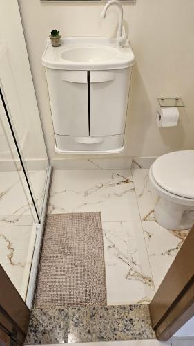 a white bathroom with a sink and a toilet at Cantinho na Serra - Apartamento in Santa Maria Madalena