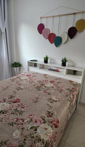a bedroom with a bed with a floral bedspread and hearts on the wall at Cantinho na Serra - Apartamento in Santa Maria Madalena
