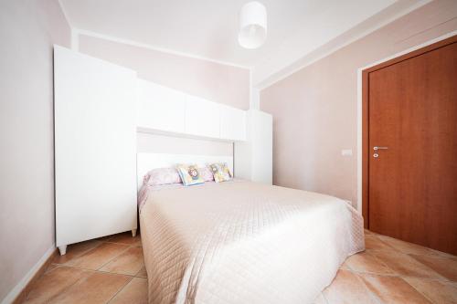 a white bedroom with a bed and a wooden door at Cas'Aurora in Tresnuraghes