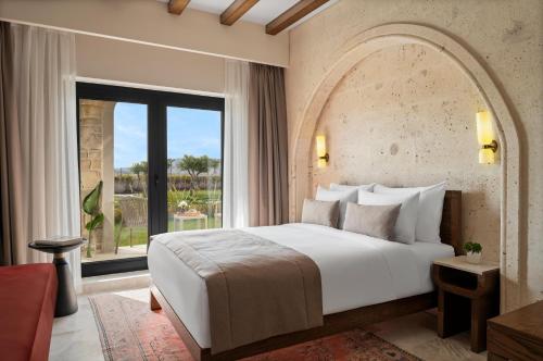 a bedroom with a large bed and a large window at Alden Hotel Cappadocia in Urgup