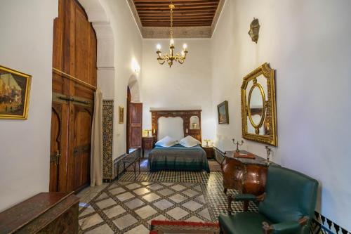 a bedroom with a bed and a chair and a mirror at Ryad Mabrouka in Fès