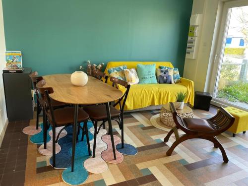 un salon avec une table et un canapé jaune dans l'établissement Charmante maison individuelle proche du Touquet, à Cucq