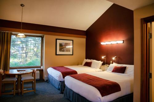 ein Hotelzimmer mit 2 Betten, einem Tisch und einem Fenster in der Unterkunft The Inn at Crumpin-Fox in Bernardston