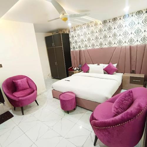 a bedroom with a bed and two purple chairs at Hotel B R Lounge in Multan