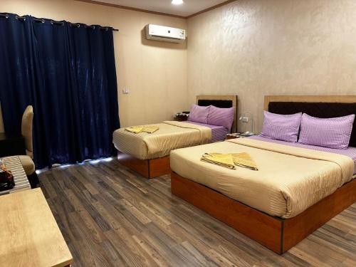 two beds in a room with blue curtains at Narmer Pyramids View in Cairo