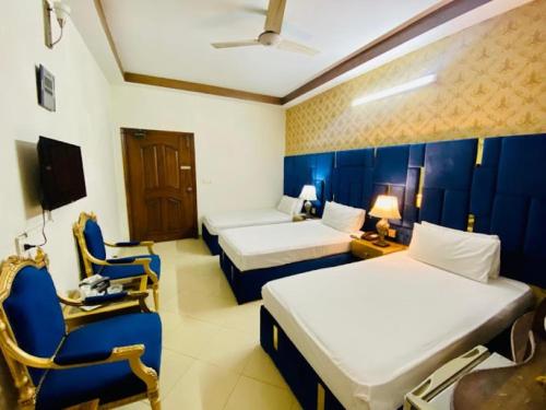 a hotel room with two beds and a chair at Hotel B R Lounge in Multan