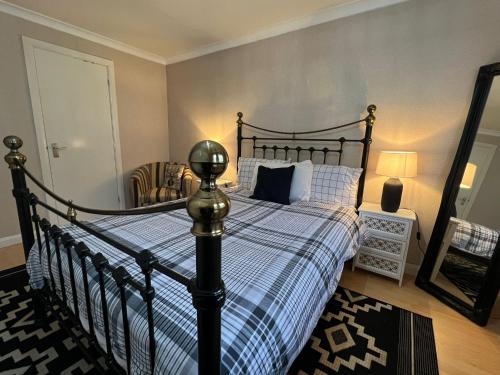 a bedroom with a black bed with a blue and white blanket at Executive double bedroom with en-suite in Easthampstead