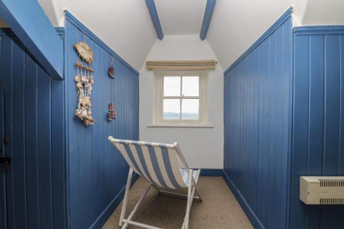 a blue room with a chair and a window at Lookout in Mousehole