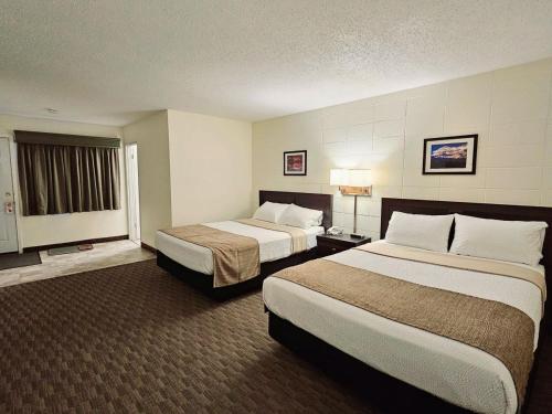 a hotel room with two beds and a window at Canadian Motor Inn in Grande Prairie