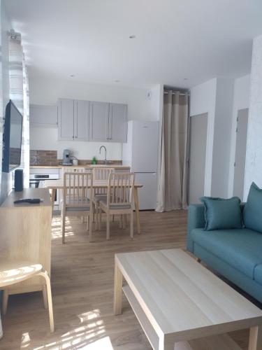 un salon avec un canapé bleu et une cuisine dans l'établissement V.KLS Appartement 3, à Languidic