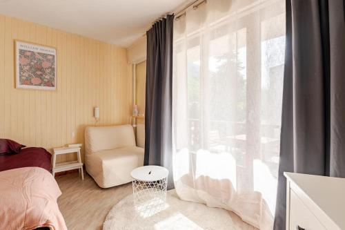 une chambre avec un lit et une fenêtre avec une chaise dans l'établissement Studio central Brides-les-Bains, à Brides-les-Bains