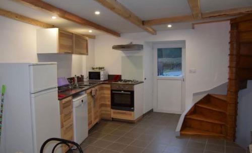 a kitchen with a white refrigerator and a stove at Gîte du Sabotier in Saint-Bonnet-près-Orcival