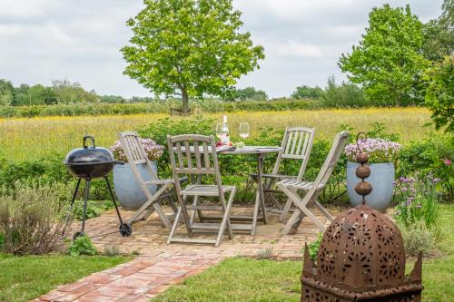a patio with a table and chairs and a grill at Elegant luxurious cottage - The Dove House in Ipswich