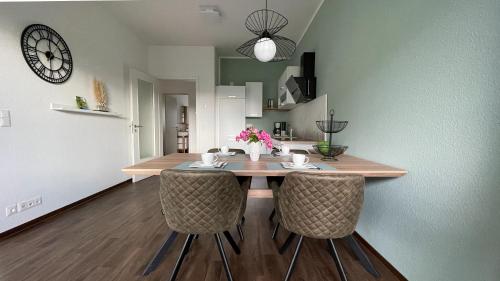 a dining room table with chairs and a clock on the wall at Ferienwohnung am Gurkenradweg in Werben