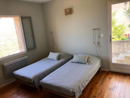 deux lits dans une chambre avec deux fenêtres dans l'établissement Villa vue imprenable mer et montagne, à Cateri