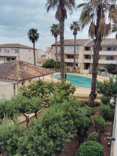 un complexe avec piscine et palmiers dans l'établissement Mayflower, au Grau-du-Roi