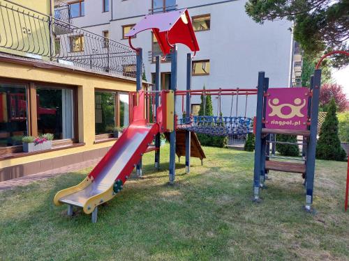 um parque infantil com um escorrega em frente a um edifício em Twoja Przystań Rodzinna em Jastrzebia Gora