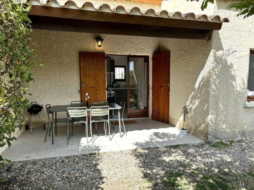 un patio avec une table et des chaises devant une maison dans l'établissement L'Escale aux portes des Gorges de l'Ardèche, à Saint-Martin-dʼArdèche