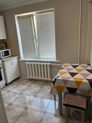 a kitchen with a table and a window and a microwave at Уютная квартира в 4 мкр Авангарда in Atyraū