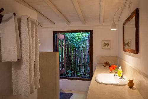ein Bad mit einem Waschbecken und einem Fenster in der Unterkunft Casa Tamy in Trancoso