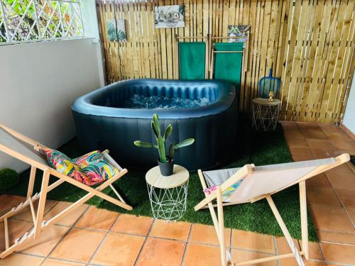 a hot tub in the middle of a yard with two chairs at Les Tuiles Rouges in Fort-de-France