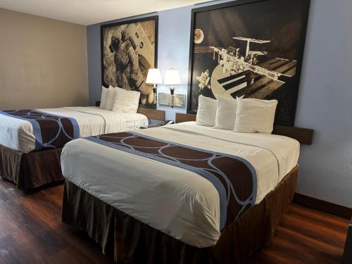 una habitación de hotel con 2 camas y un cuadro en la pared en Super 8 by Wyndham Houston Webster NASA, en Webster