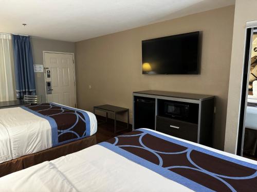 a hotel room with two beds and a flat screen tv at Super 8 by Wyndham Houston Webster NASA in Webster