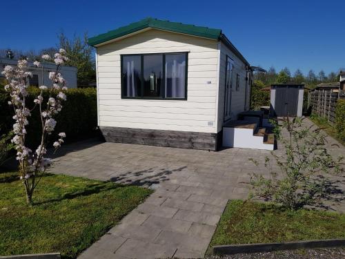 a white shed with a window on a patio at Cozy chalet near Amsterdam at Camping Venhop in Berkhout