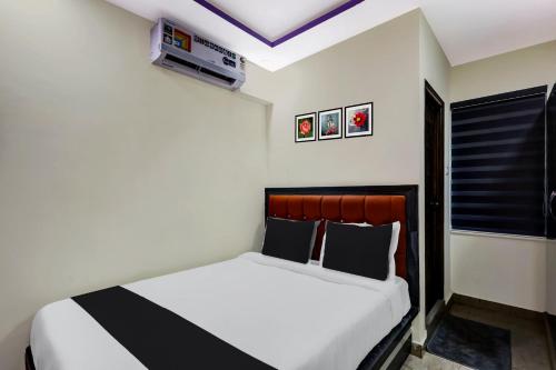 OYO AADYA INN في تيروباتي: غرفة نوم بسرير ابيض مع مخدات بيضاء وسوداء