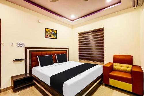 1 dormitorio con 1 cama grande y 1 silla en OYO AADYA INN, en Tirupati