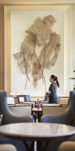 a woman in a room with a painting on the wall at Shangri-La Tangshan in Tangshan