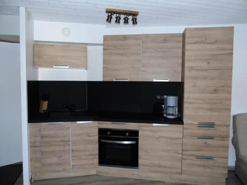 une cuisine avec des armoires en bois et un appareil noir dans l'établissement Résidence Thabor - 2 Pièces pour 4 Personnes MAE-8574, à Modane