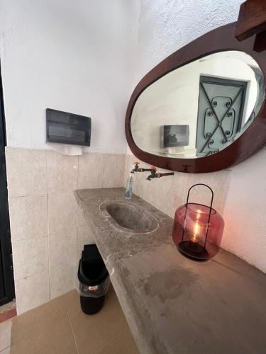 a bathroom with a sink with a mirror and a candle at Hostal Luna 49 in Querétaro
