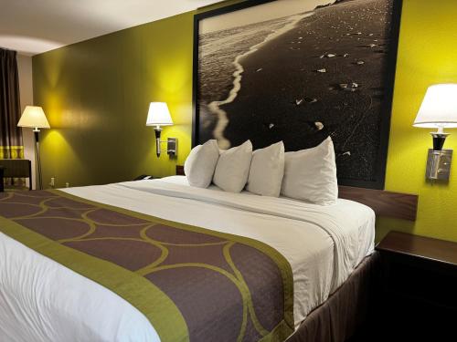 a large bed in a hotel room with yellow walls at Super 8 by Wyndham Houston Webster NASA in Webster