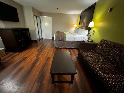 a hotel room with a bed and a couch at Super 8 by Wyndham Houston Webster NASA in Webster