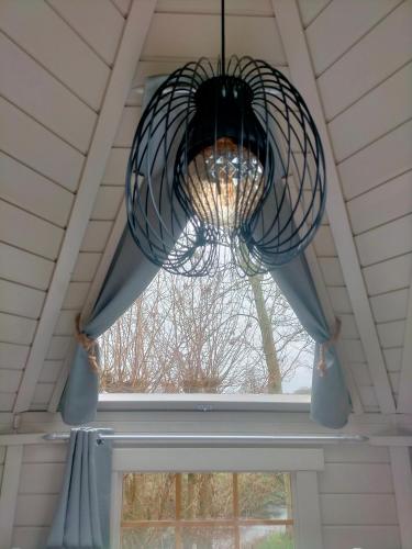 a chandelier hanging from a ceiling with a window at Sterrenzicht BB Weidszicht in Doezum