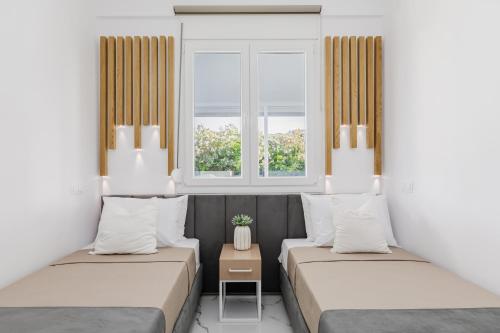 two beds in a room with two windows at Stork Apartments in Hanioti