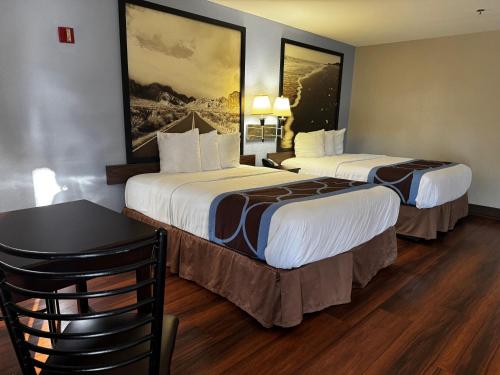 a hotel room with two beds and a table at Super 8 by Wyndham Houston Webster NASA in Webster