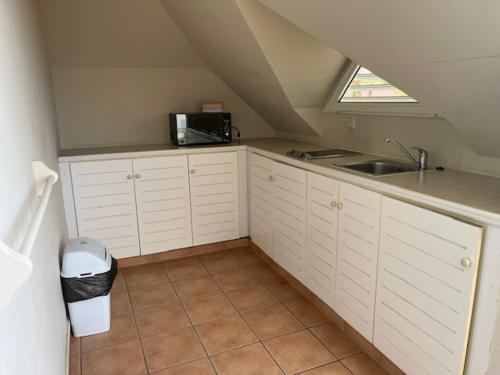a kitchen with white cabinets and a sink and a window at TROPIC Appartements PREMIUM village pierre et vacances vue mer Martinique in Sainte-Luce