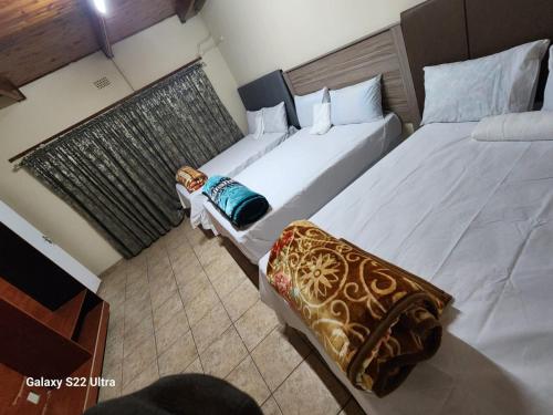 two beds in a hotel room with two bedsskirts at WAMPEX GUEST HOUSE IN RUSTENBURG in Rustenburg