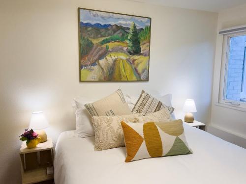 a bedroom with a white bed with pillows and a painting at Magnolia Garden Cottage in Seattle