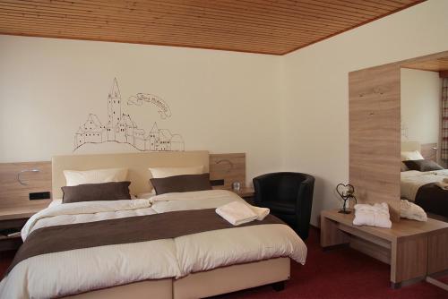 a bedroom with a large bed with a desk and a chair at Landgasthof Fischer Veri in Mitterfels