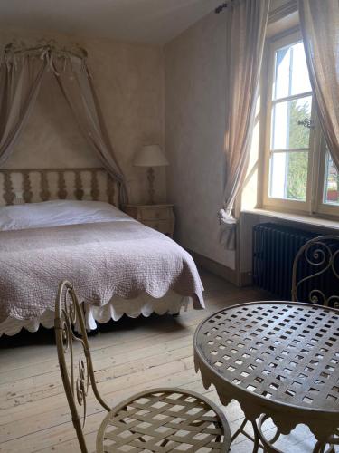 a bedroom with a bed and a table and chairs at Les Jardins de la Tour in Châtillon-sur-Chalaronne