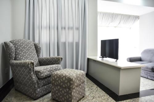 a living room with a chair and a tv at Plaza Inn Small Town Flat in Sao Paulo